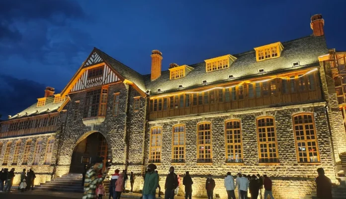 Heritage stone building in Shimla lit up in the evening with visitors outside