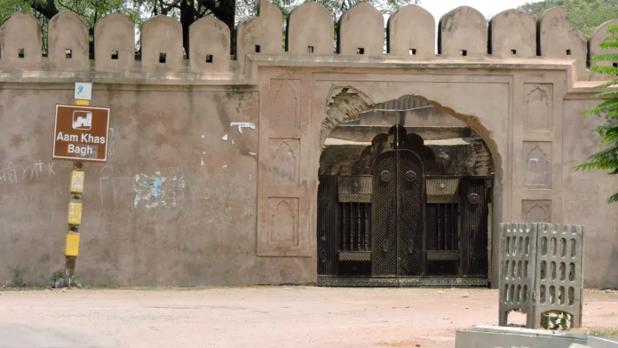 Arched entrance of Aam Khas Bagh in Sirhind, with wooden doors in a crenellated wall and a brown Aam Khas Bagh sign