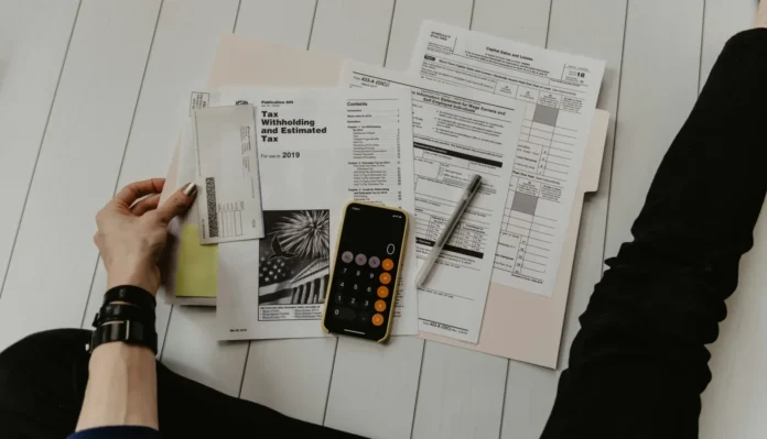Person reviewing tax forms with a calculator and pen on a white desk