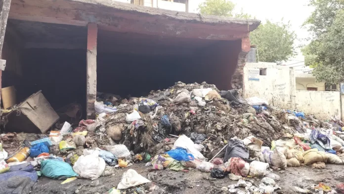 Heap of plastic bags and household waste dumped under an open shed beside a road