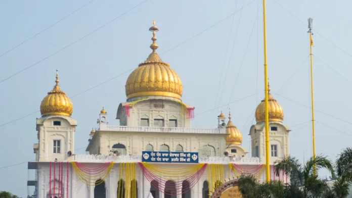 Main building of Gurdwara Fatehgarh Sahib in Sirhind with golden domes and colourful garlands, under a clear blue sky