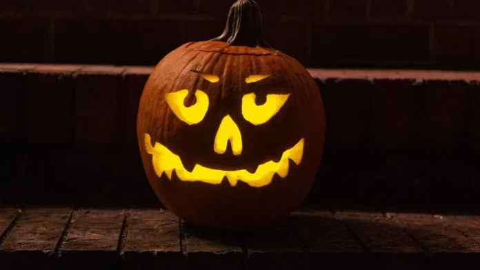 Carved jack-o'-lantern pumpkin glowing yellow on a dark step at night