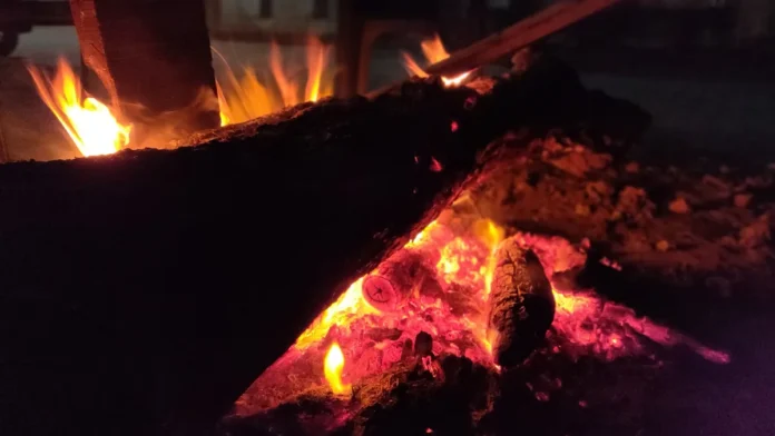 Burning logs and glowing embers of a Lohri bonfire at night in Patiala