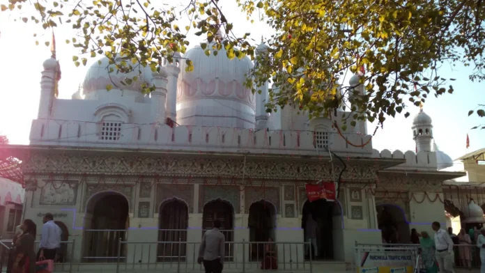 White domes and arched front of the main shrine at Mata Mansa Devi Temple near Panchkula, with visitors at the entrance