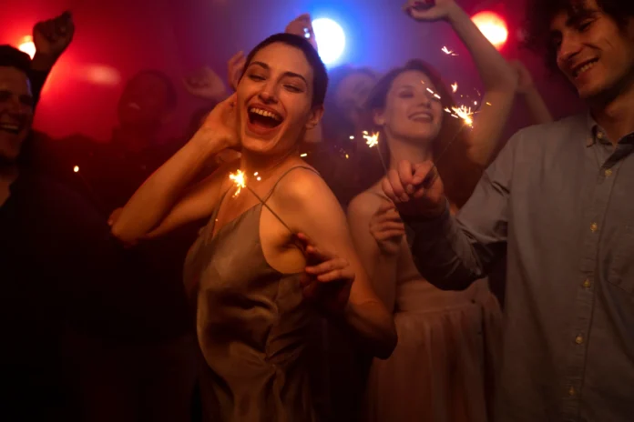 People celebrating with sparklers at a crowded New Year party