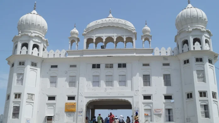 White building with domed towers at the Takht Sri Kesgarh Sahib complex in Anandpur Sahib, with visitors under its arched gateway