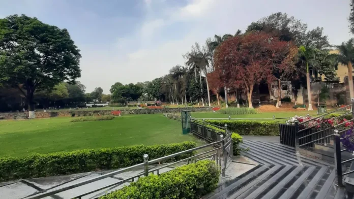 Stone terraces with hedges and steel railings stepping down to the main lawn and trees at Terraced Garden, Sector 33, Chandigarh