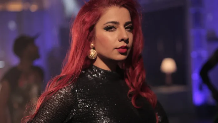 Jasmine Sandlas in a black sequinned top with long red hair