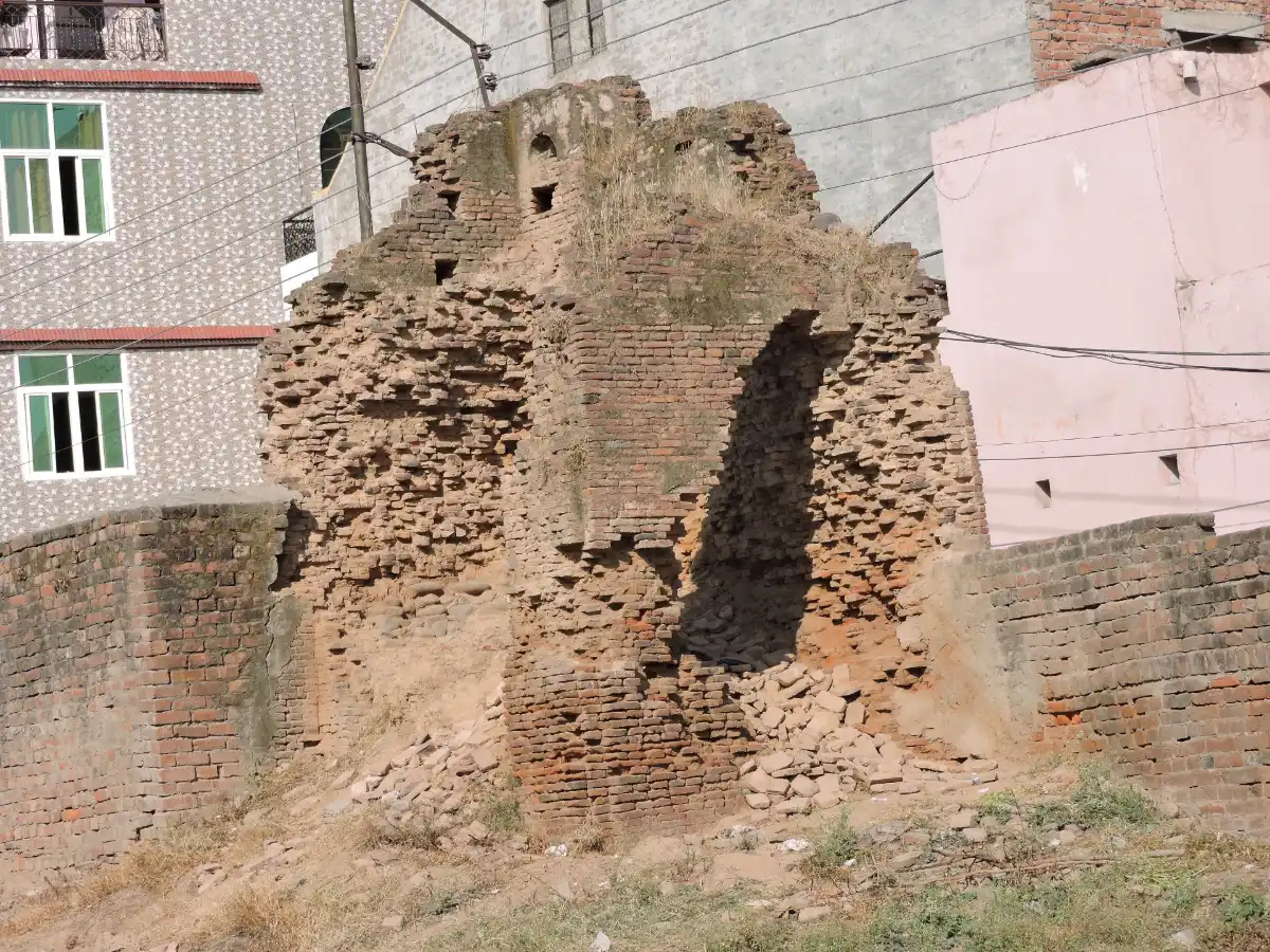Manimajra Fort, Chandigarh: History, Condition And How To Visit 1 Crumbling brick section of Manimajra Fort with fallen bricks at its base, hemmed in by a brick wall and modern buildings