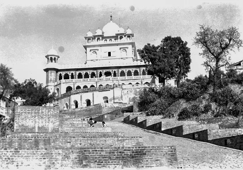 Black and white photograph of Takht Kesgarh Sahib on its hill with a brick-paved approach in the foreground, taken around 1952